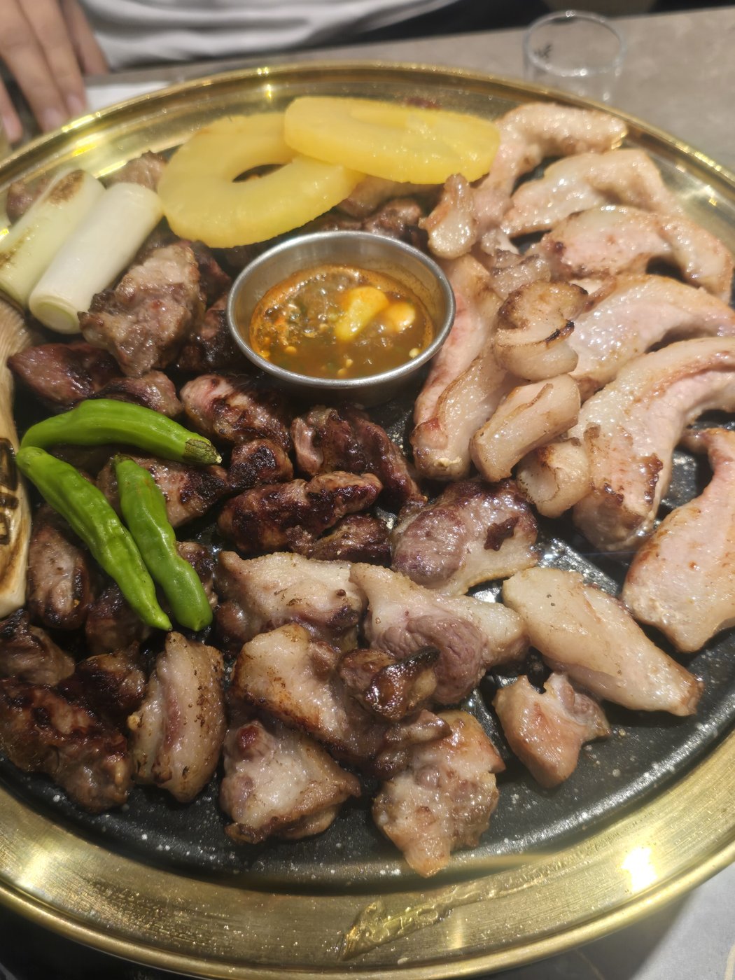구운 돼지고기 조각과 파인애플, 대파, 꽈리고추가 올라간 불판